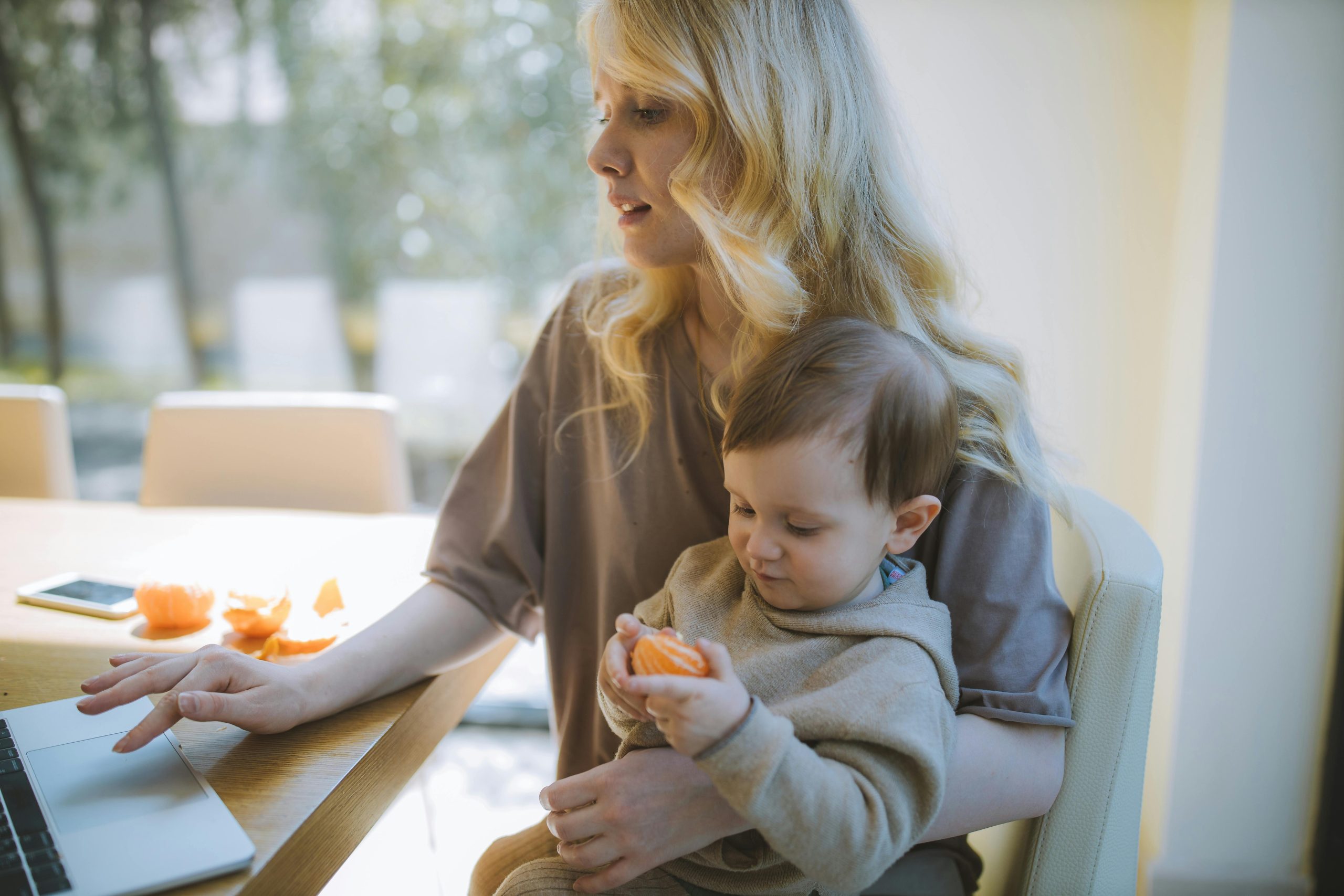 A woman with a young child and family searching on the computer for life insurance options with the AS Financial website on her computer screen